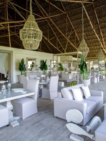 Elegantes Restaurant mit weißer Einrichtung und traditionellem Strohdach