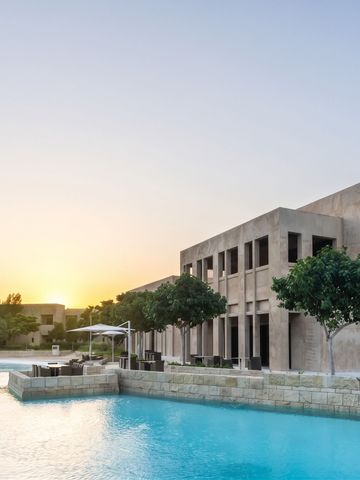 Infinity-Pool bei Sonnenuntergang mit Architektur im Hintergrund