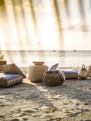 Entspannter Strandbereich mit Korbmöbeln und Blick aufs Meer