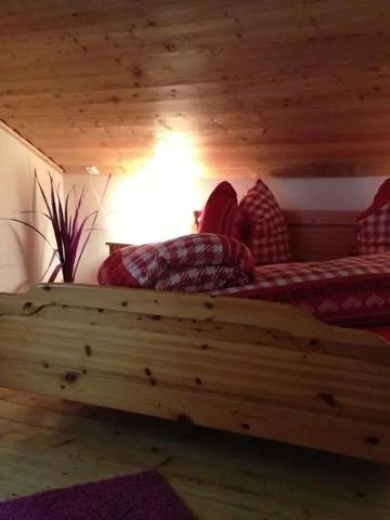 Gemütliches Schlafzimmer mit Holzdecke und rotem Bett