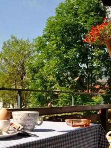 Frau auf Terrasse mit Bergblick und Frühstückstisch