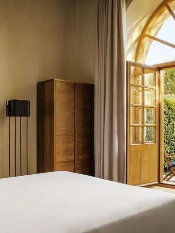 Luxuriöses Hotelzimmer mit Blick auf einen privaten Garten durch große Glastüren.