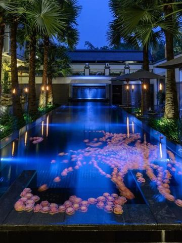 Beleuchteter Pool bei Nacht mit schwimmenden Blumen