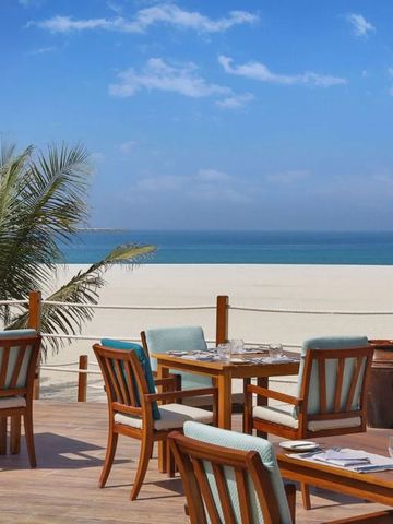 Terrasse mit Tischen und Stühlen direkt am Strand