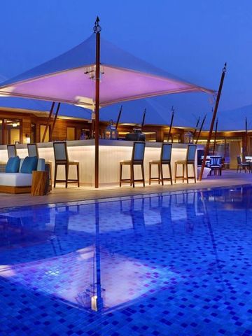 Stilvolle Bar am Pool bei Nacht mit beleuchteten Sonnenschutzdächern