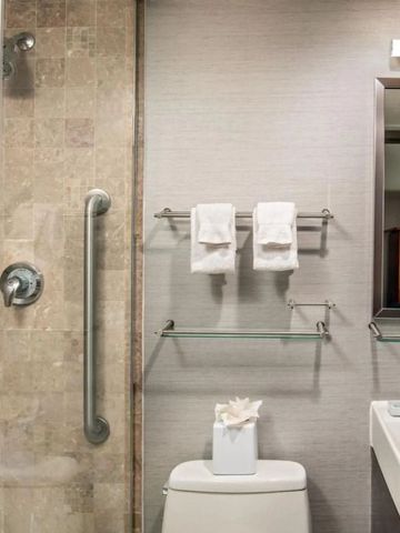 Moderner Hotelbadbereich mit eleganter Duschverkleidung und Handtuchhalter