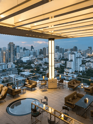 Die Nimitr Terrace der 137 Pillars Suite Bangkok erstrahlt im warmen Licht des Sonnenuntergangs. Von der offenen Terrasse aus bietet sich ein atemberaubender Blick über die Skyline