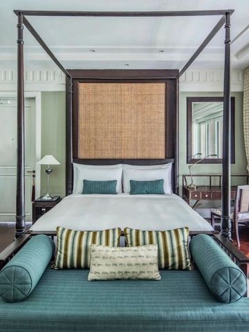 Schlafzimmer mit Himmelbett und grünen Akzenten vor großen Fenstern