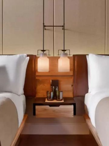 Nahaufnahme von zwei Hotelbetten mit geschmackvoller Beleuchtung und Holzdetails.