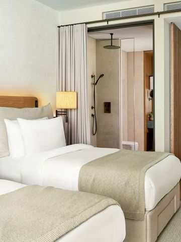 Doppelzimmer mit zwei Einzelbetten und offener Dusche