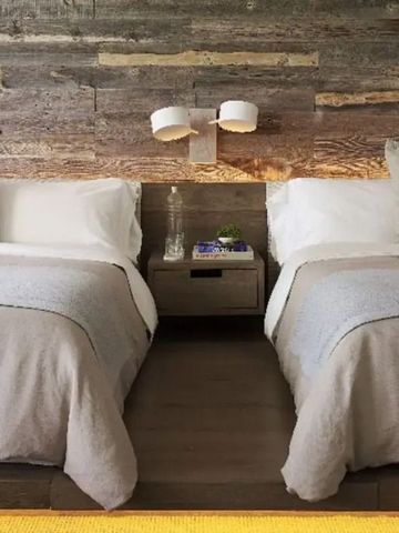 Zwei Doppelbetten in einem Zimmer mit rustikaler Holzwand