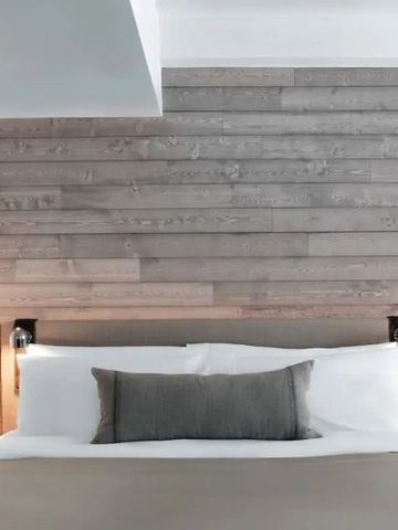 Zimmer im minimalistischen Design mit Holzwand und bequemem Bett