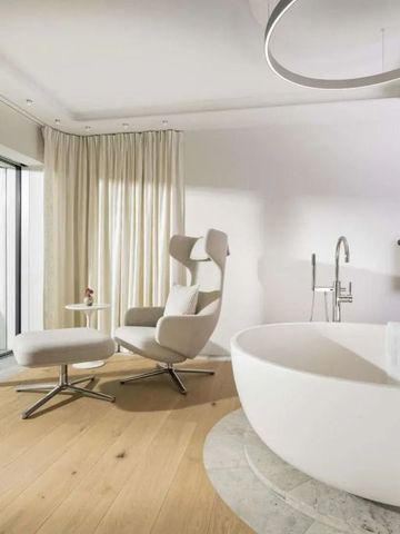 Geräumiges Badezimmer mit freistehender Badewanne und Liegesessel