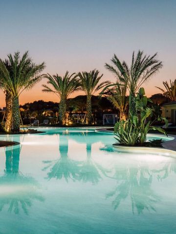 Infinity Pool bei Sonnenuntergang umgeben von Palmen