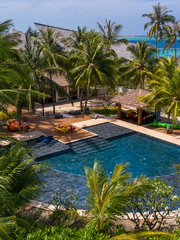 Tropische Resort-Poollandschaft umgeben von Palmen mit Blick auf das Meer