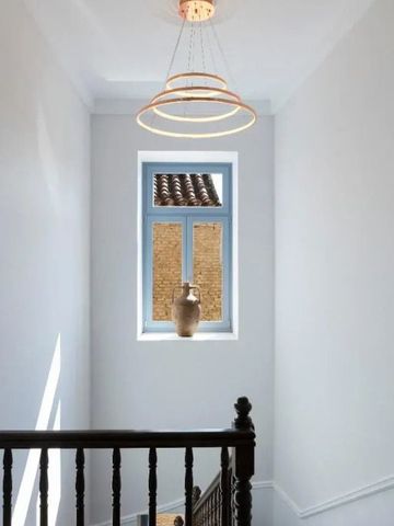 Helle Treppenhaus-Ecke mit Dekovase und modernem Leuchter