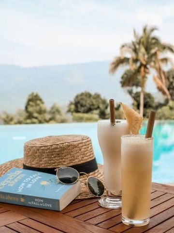 Cocktails und Hut neben einem Infinity-Pool mit Bergen im Hintergrund