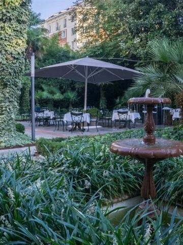 Grüner Garten mit Springbrunnen und Sitzbereich unter großen Schirmen