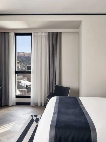 Helles Hotelzimmer mit großem Fenster und Blick auf die Stadt