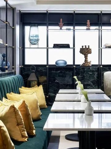 Eleganter Restaurantbereich mit grünen Sofas und gelben Kissen