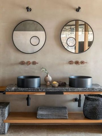 Modernes Badezimmer mit Doppelwaschbecken und Spiegeln an einer eleganten Steinoberfläche