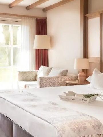 Großes, gemütliches Hotelzimmer mit Holzbalken und moderner Einrichtung