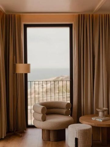 Gemütlicher Loungebereich mit Blick auf das Meer durch ein großes Fenster