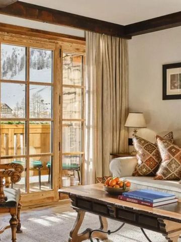 Gemütliches Wohnzimmer mit Holzbalkendecke und Blick auf verschneite Landschaft