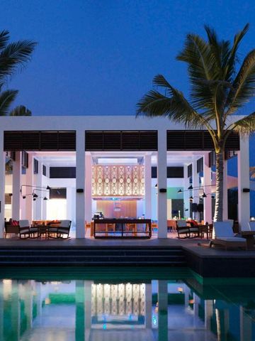 Elegantes Restaurant am Pool beleuchtet bei Nacht im Al Baleed Resort Salalah.