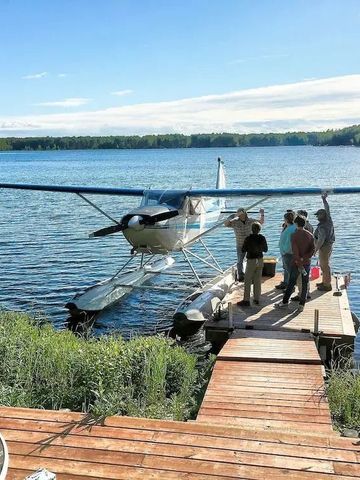 Wasserflugzeug an einem Steg auf einem ruhigen See inmitten der Natur