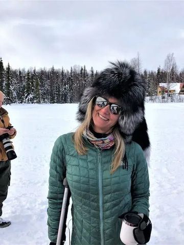 Frau in Winterkleidung mit Tasse, verschneite Landschaft im Hintergrund