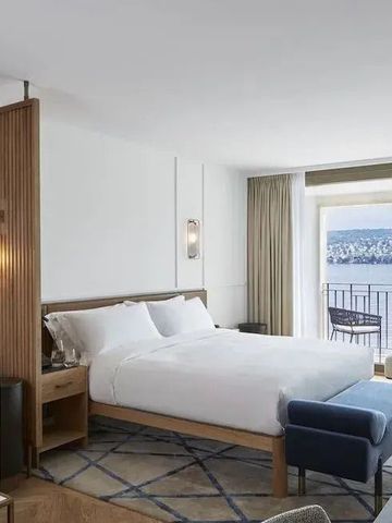 Helles Hotelzimmer mit Doppelbett und Seeblick vom Balkon