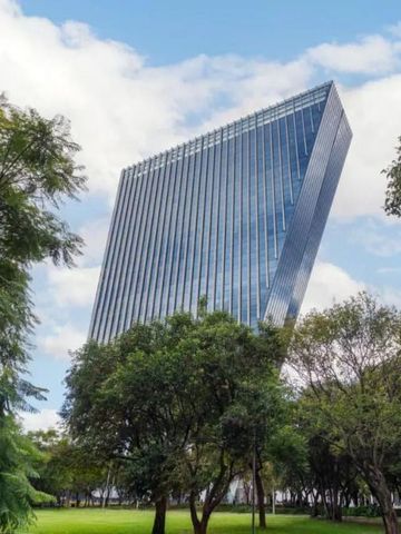 Moderne Fassade eines schrägen Hochhauses mit Glasfront und Bäumen im Vordergrund