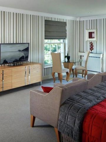 Geräumiges Zimmer mit Streifenmuster und großem TV