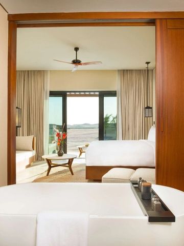 Elegantes Hotelzimmer mit freistehender Badewanne und Blick auf Terrasse