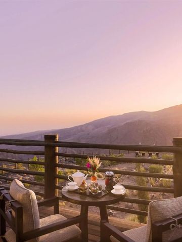 Terrasse mit Sitzbereich und Panoramablick auf die Berge bei Sonnenuntergang.