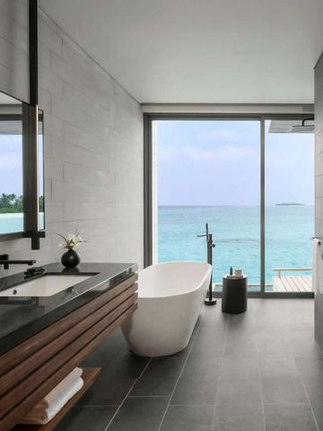 Stilvolles Badezimmer mit freistehender Wanne und Panoramablick auf das Meer