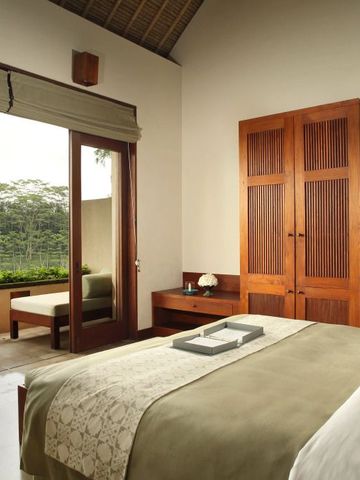 Gemütliches Hotelzimmer mit Holzschränken und großem Fenster mit Gartenblick