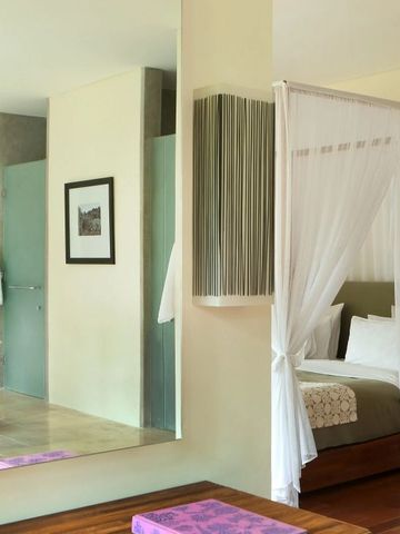 Elegantes Zimmer mit Himmelbett und modernem Spiegel in Alila Ubud.
