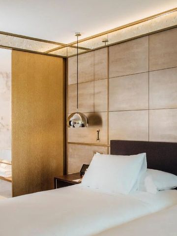 Gemütliches Hotelzimmer mit edler Wandverkleidung und luxuriöser Bettwäsche