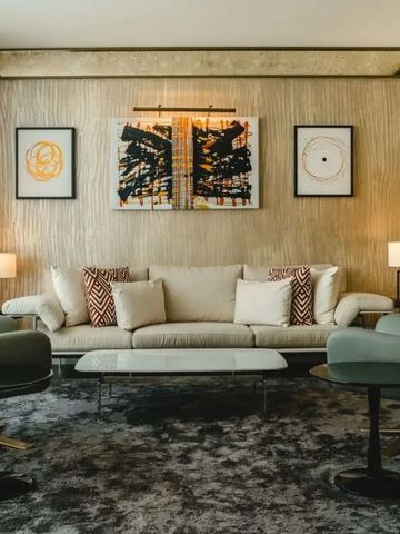 Stilvolles Wohnzimmer mit beiger Couch, Kunstwerken und modernen Sesseln