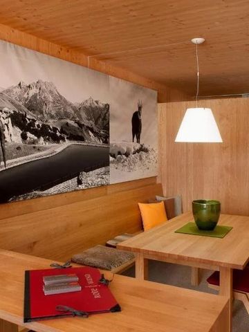 Gemütliche Sitzecke mit Holztisch und Wandbild einer Berglandschaft