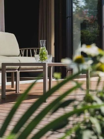 Sonnige Terrasse mit moderner Sitzgruppe und grüner Umgebung