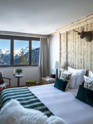 Helles Schlafzimmer mit Panoramablick auf verschneite Berge. Stilvoller Holzkopfteiler.