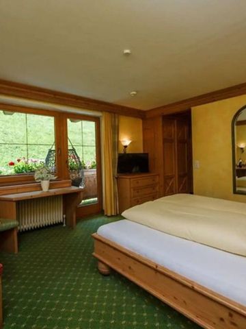 Traditionelles alpines Zimmer mit Holzmöbeln und Balkon.