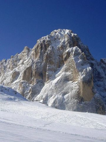 Verschneite Berglandschaft in den Dolomiten unter strahlend blauem Himmel