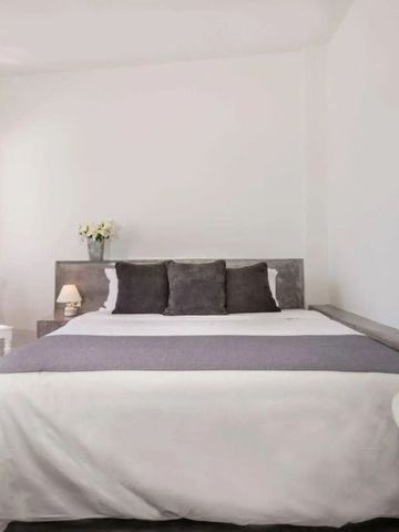 Minimalistisch eingerichtetes Schlafzimmer mit großen Fenstern und Tageslicht