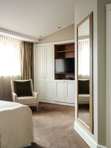 Helles Gästezimmer mit bequemen Sessel und Fernseher