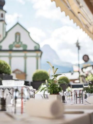 Elegant gedeckter Tisch auf einer Terrasse mit Bergblick und Kirche im Hintergrund