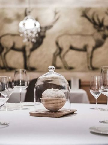 Gedeckter Tisch in einem Restaurant mit kunstvollen Hirschmalereien an der Wand